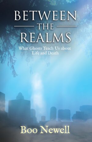 A book cover titled "Between the Realms" with the subtitle "What Ghosts Teach Us About Life and Death" by Boo Newell, featuring a misty graveyard scene.