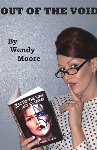 Woman posing with a finger to her lips, holding a book titled "Out of the Void" while standing next to text "Out of the Void, by Wendy Moore.