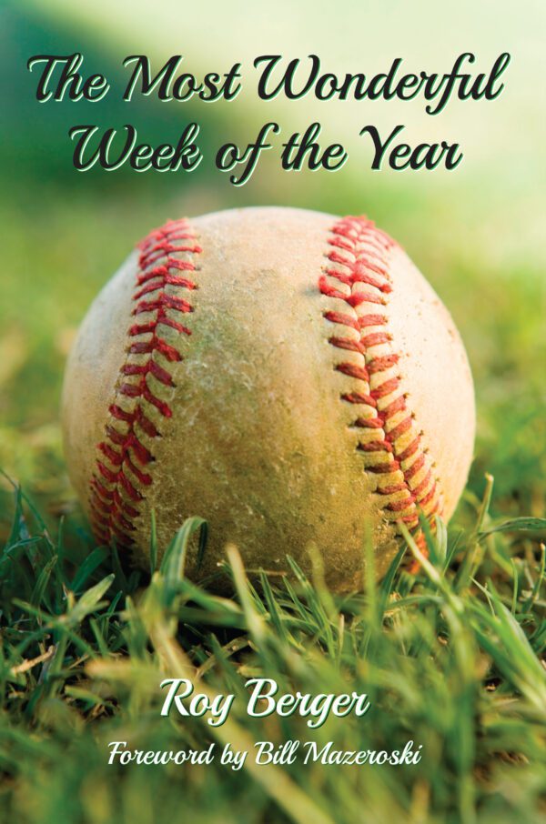 A well-used baseball lying on grass with The Most Wonderful Week of the Year by Roy Berger, featuring a foreword by Bill Mazeroski.