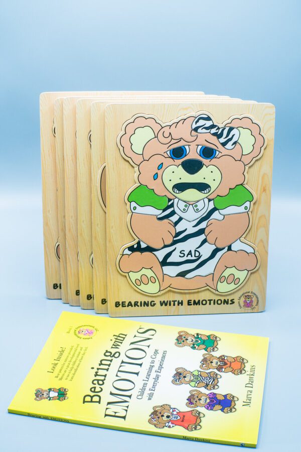 Educational children's book and puzzle set titled "Bearing with Emotions Book and Puzzle Set" featuring an illustration of a bear with contrasting happy and sad facial expressions.