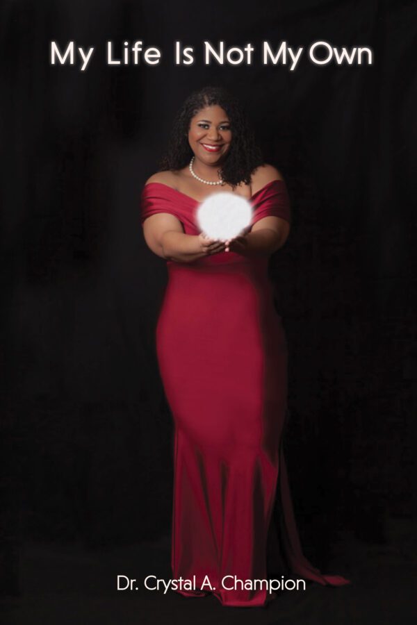 A woman in a red dress holding a glowing orb with the text "My Life Is Not My Own" above and "Dr. Crystal A. Champion" below.