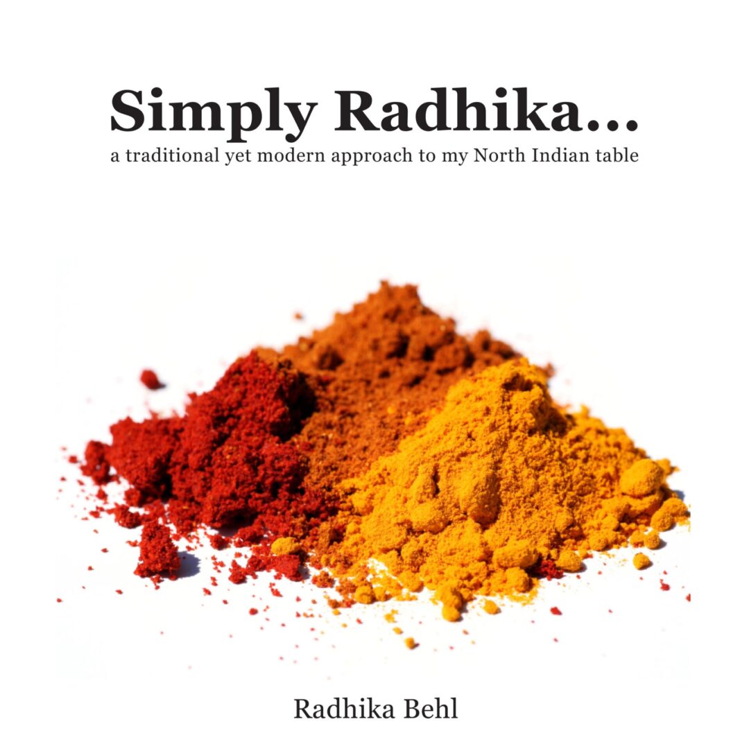 Piles of colorful spices on a white background with the title "Simply Radhika... a traditional yet modern approach to my North Indian table" by Radhika Behl.