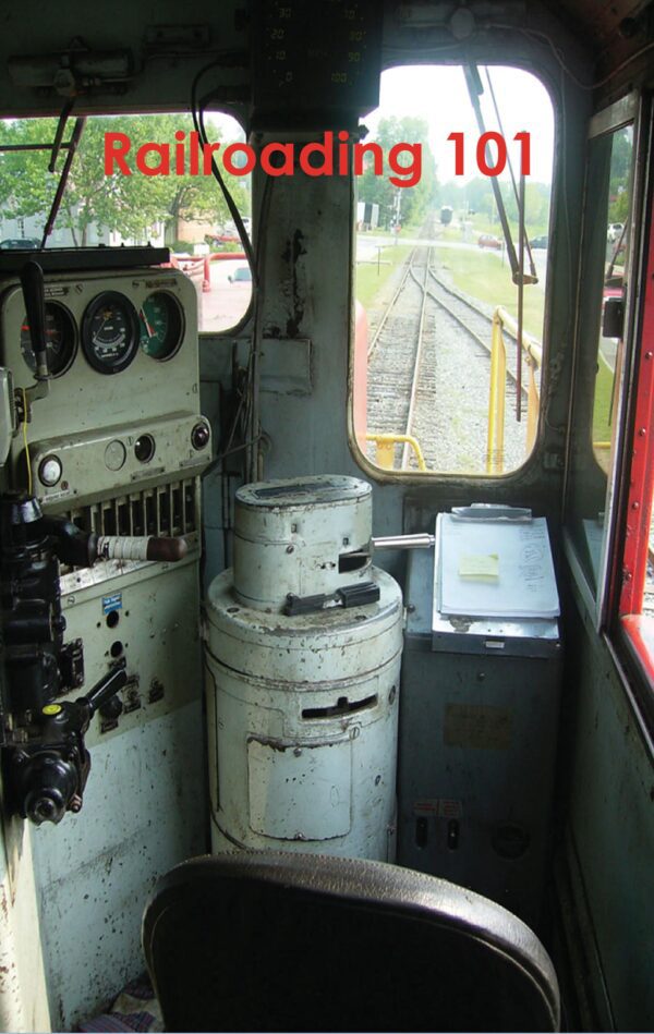 View from a Railroading 101's cab with control instruments, overlooking tracks ahead.