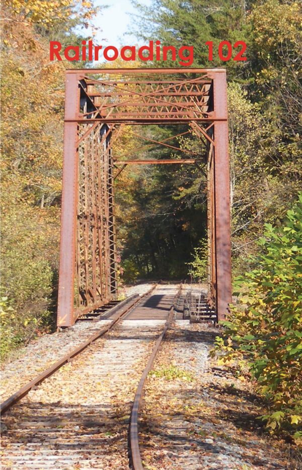 Abandoned Railroading 102 tracks leading through a rusted metal bridge surrounded by autumn foliage.