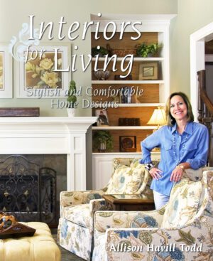 A smiling woman stands confidently in a tastefully decorated living room featured on the cover of Interiors for Living magazine.