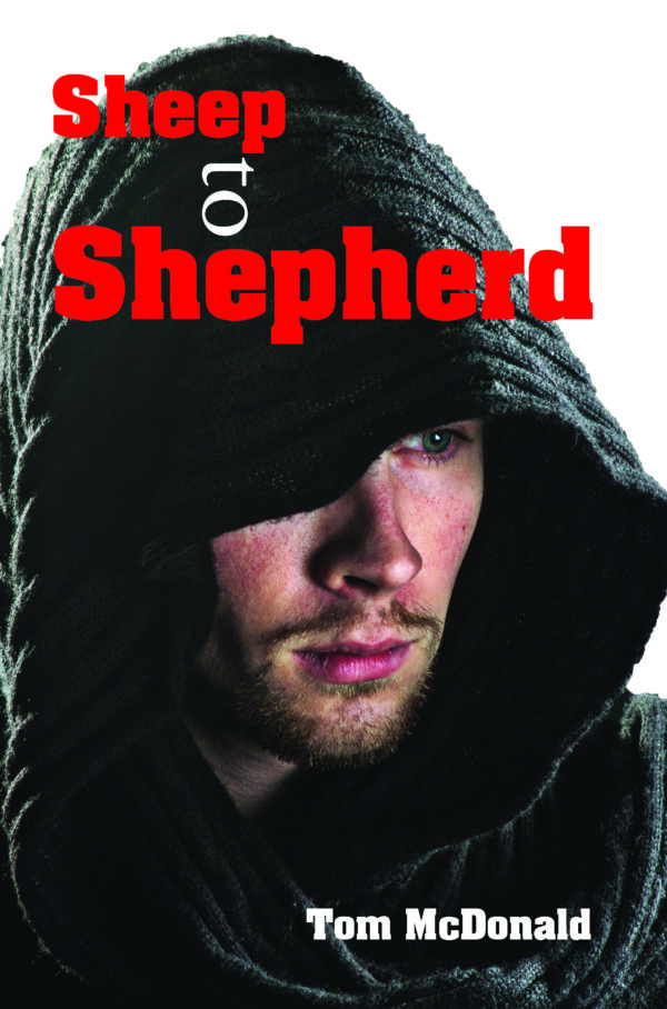 A man wearing a dark hooded garment with the product "Sheep to Shepherd" written in red and the author's name "Tom McDonald" below.