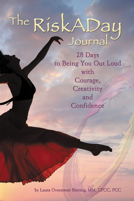 A book cover titled "The RiskADay Journal" featuring a silhouette of a woman dancing against a sunset sky.
